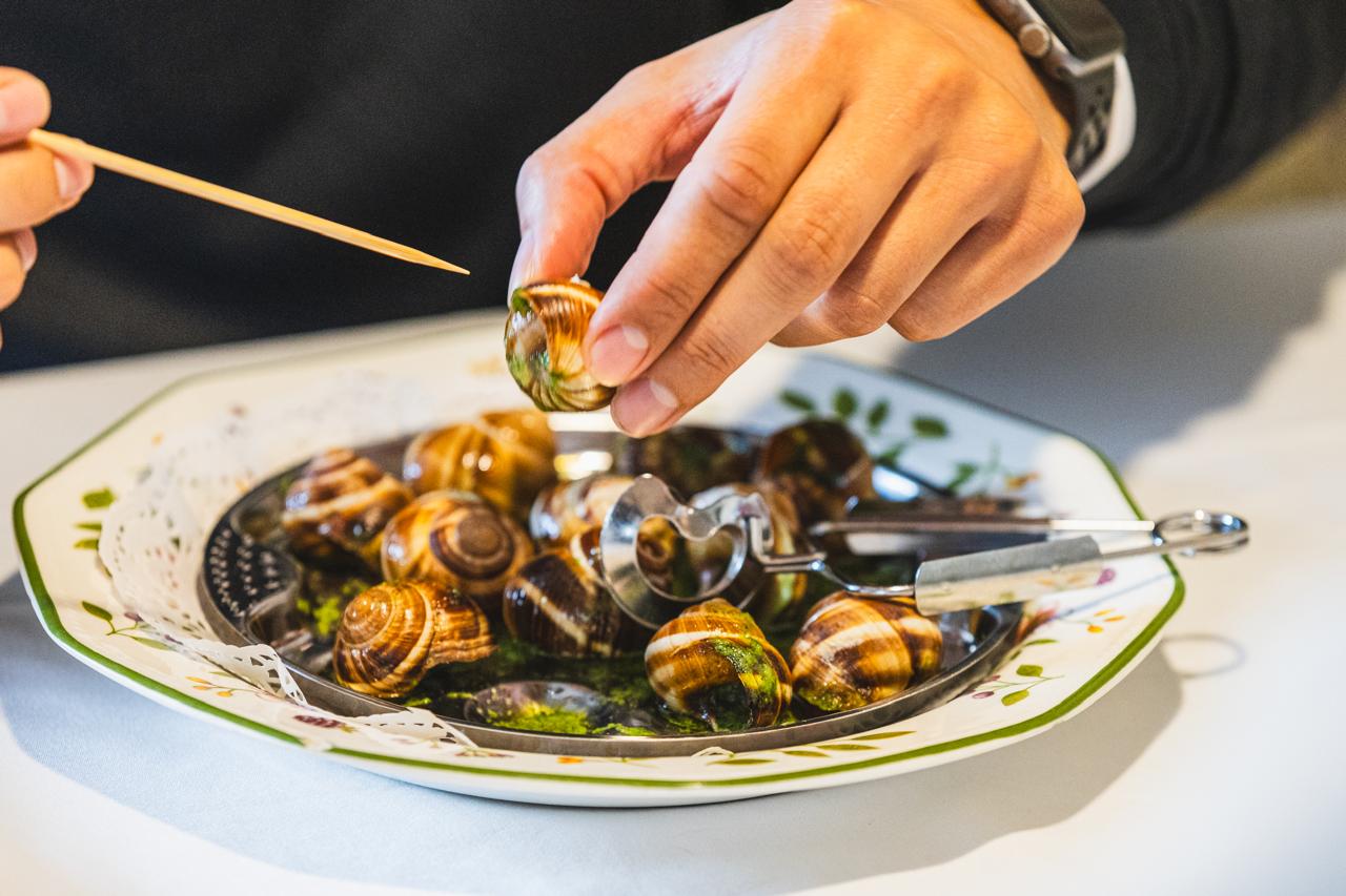 ✨ Cargols de Borgonya a l’Era d’en Jaume ✨ Un clàssic amb història… i amb molta més vida del que sembla. En el món gastronòmic, els cargols a la borgonyona —”escargots à la bourguignonne”— són tota una institució. Un plat nascut a París l’any 1814, durant un àpat organitzat pel diplomàtic i gastrònom Talleyrand en honor del tsar Alexandre I. El cuiner, Anacréon, borgonyó de naixement, va voler homenatjar la seva terra amb aquests caragols grossos, cuinats amb vi blanc i farcits amb mantega i fines herbes. Amb el temps, els francesos han creat tot un ritual al voltant d’aquest plat: safates especials, pinces expresses i una litúrgia que ha inspirat llibres, cinema i sèries. Fins i tot el tinent Colombo s’hi va trobar embolicat en un episodi, desconcertat davant l’“excentricitat” d’un nord-americà menjant cargols… que, evidentment, acabava sent el culpable. A l’Era d’en Jaume, els servim amb respecte per la tradició i passió pel producte. Una mossegada amb història, caràcter i un punt de sofisticació que no deixa ningú indiferent. 🐌✨ Vine a tastar-los i descobreix per què aquest clàssic continua captivant paladars de tot el món.